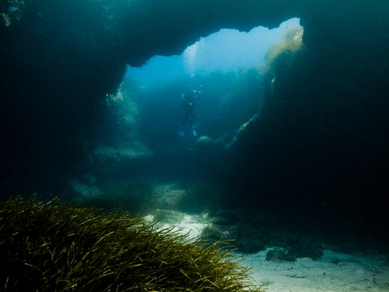 Diver at Cirkewwa Arch at Cirkewwa Marine Park, Malta.